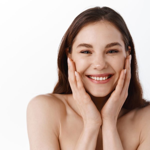 Happy beautiful girl holding her cheeks with a laugh looking to the side. Pretty woman clean fresh skin . Expressive facial expressions .Cosmetology , beauty and Spa.